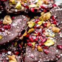 A pile of holiday bark on the table topped with pomegranate seeds and pistachios.