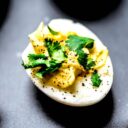 A deviled egg without mayo garnished with cilantro on a plate.