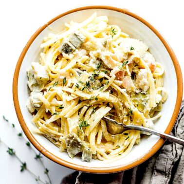 A bowl of white wine pasta on the table with a fork in the bowl.