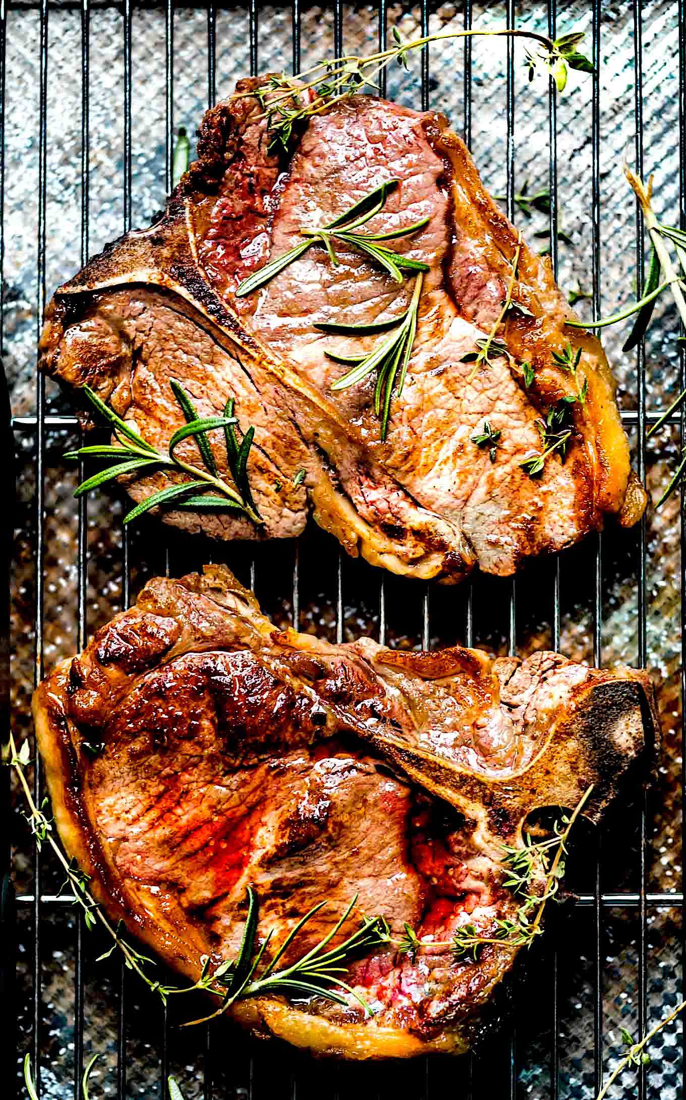 Two t-bone steaks on a grill pan after cooking.