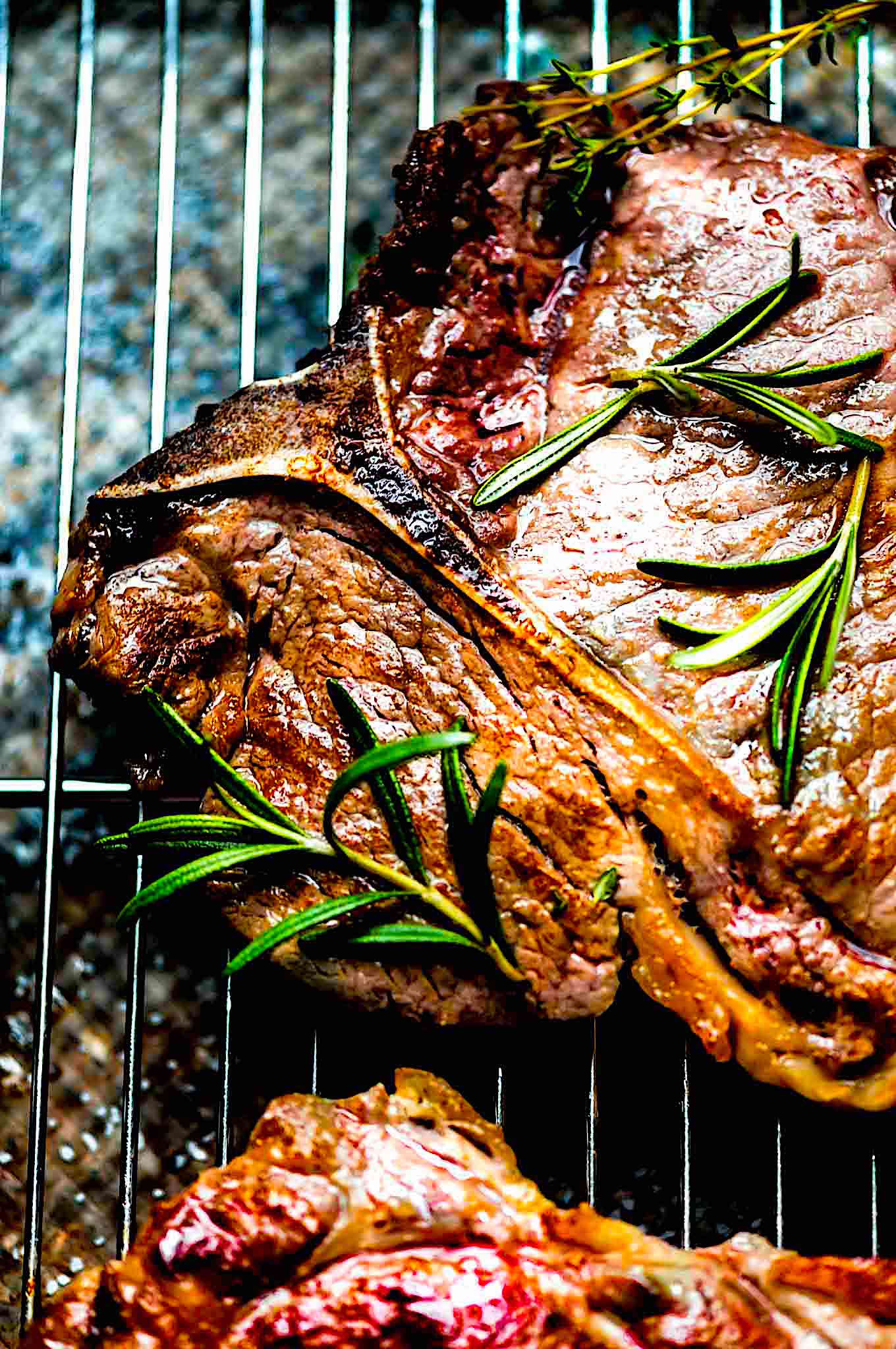 A t-bone steak on a grill pan with pieces of rosemary.