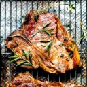 A t-bone steak cooked in a skillet on a rack after broiling.