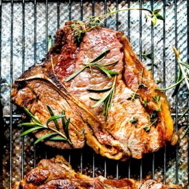 A t-bone steak cooked in a skillet on a rack after broiling.