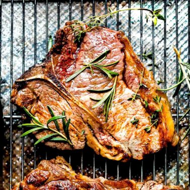 A t-bone steak cooked in a skillet on a rack after broiling.