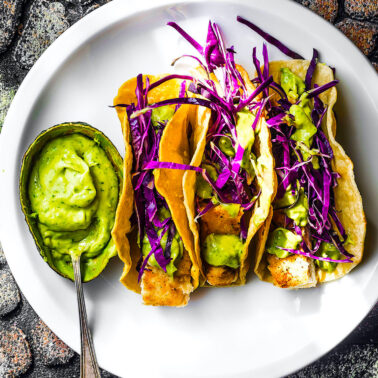 Baja Fish Tacos with sauce on the side overhead shot of white plate